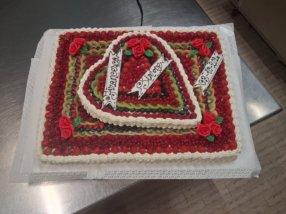 Torta nuziale alla frutta con cuore rialzato e rose rosse